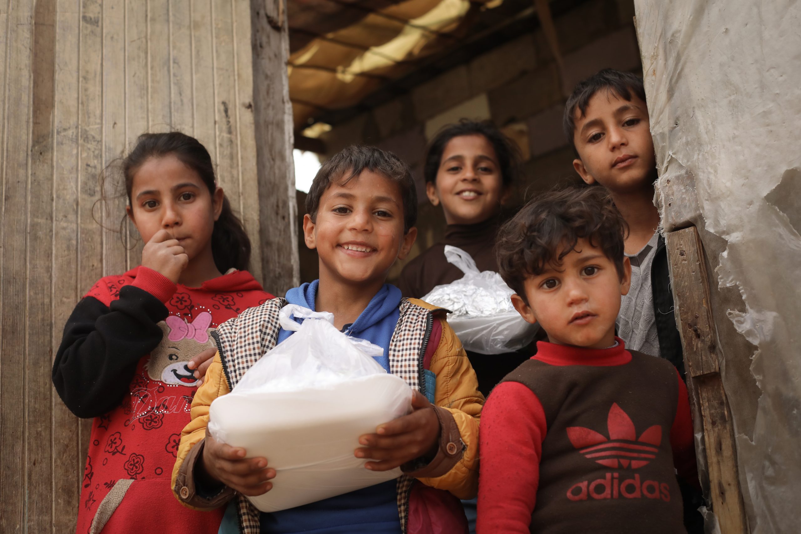 group of five young children with a to go package of food