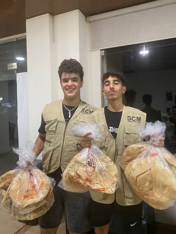 two young adult men holding plastic bags of bread
