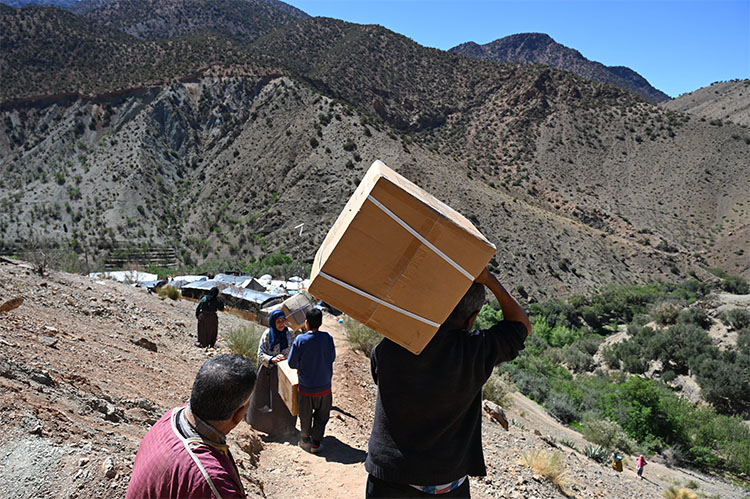 men walking with boxes of supplies on a mountainous trail