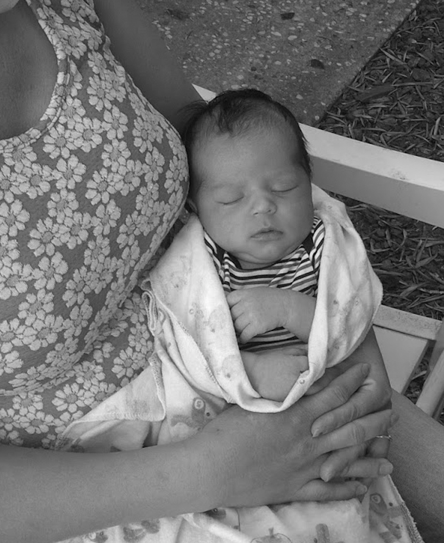infant wrapped in a blanket being held by mother