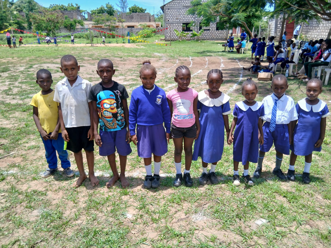 school children standing in a line on a grassy field